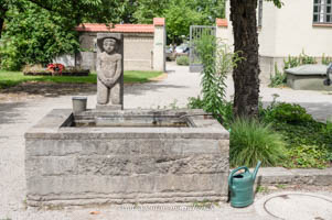 Knieender nackter Mann am Brunnen